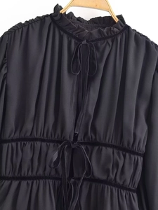 Detail of ruffled stand collar and velvet lace-up front on a black vintage blouse