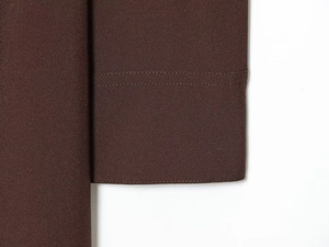 Detailed macro shot of the double-needle stitching and hem on the dark brown shirt dress