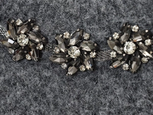 Detail of floral beaded jewelry with black marquise gems on a knit sweater