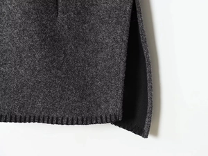 Macro detail of dark grey wool fabric with black blanket stitch trim and side slit hem