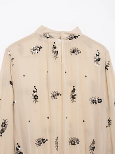Close-up of beige sheer shirt with black and silver sequin floral embroidery detail