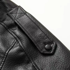 Detailed macro view of the black faux leather shoulder epaulet and stitching on biker jacket