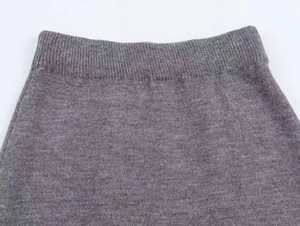 Gros plan sur la taille élastique côtelée d'une jupe en maille grise à la texture douce