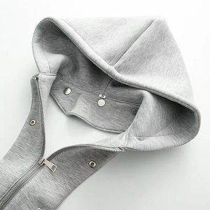 Détails de la veste grise à capuche avec fermeture éclair métallique et boutons pressions