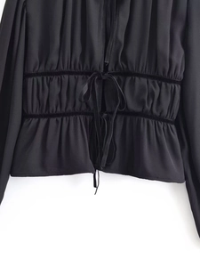 Detail of black long-sleeve top featuring shirred waist and velvet ribbon accents
