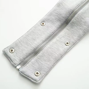 Détail du tissu tricoté gris avec fermeture éclair en métal argenté et boutons-pression