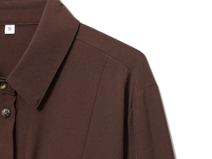 Detail shot of a dark brown woven shirt collar with tortoiseshell buttons and size S tag