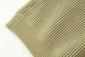 Detail shot of the olive green rib-knit texture on a stylish autumn cardigan sweater