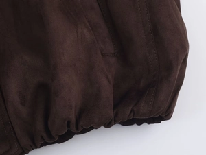 Detailed close-up of dark brown suede jacket hem with elasticated ribbed cuffs and stitching