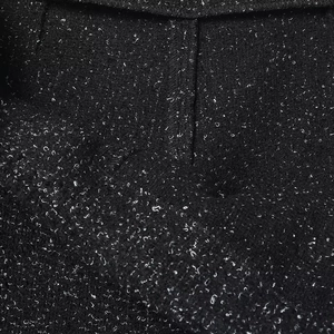 Detailed close-up of premium black flecked tweed fabric texture and sewing craftsmanship