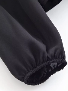 Detail view of elastic ruffled cuffs on a black vintage blouse with sheer chiffon texture