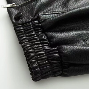 Detailed macro view of black lychee grain leather jacket with silver zipper and elastic cuff