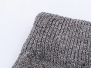 Détail de la texture maille côtelée grise avec fibres de laine sur le poignet du pull