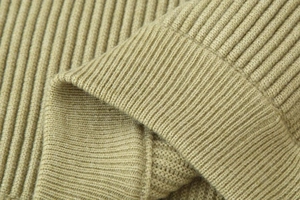 Detailed macro view of the premium ribbed knit texture and cuff stitching on sand beige sweater