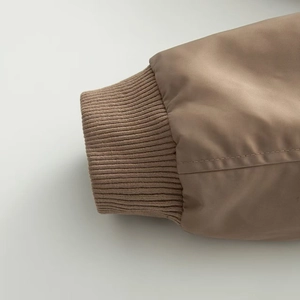 Close-up of khaki brown parka jacket with ribbed knit cuffs and smooth woven fabric detail
