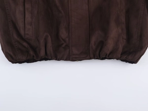 Detail of dark brown faux suede jacket featuring elastic hem and precise seam stitching