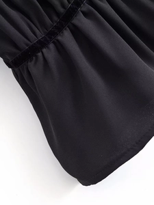 Close-up of black chiffon blouse detail featuring velvet ribbon and ruffled elastic cuffs