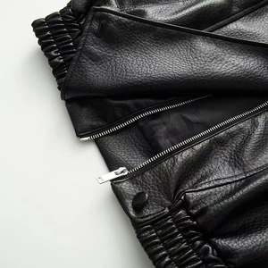 Close-up of litchi grain black leather jacket with silver zipper and matte metal snap buttons