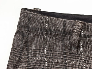 Close-up of high-waisted plaid trousers featuring grey tweed fabric and vertical white stripes