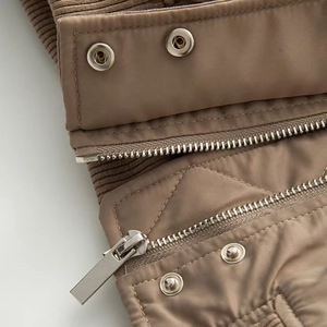 Detailed close-up of high-quality metal zipper and snap buttons on a beige winter jacket