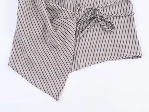 Detail of grey striped shirt showing the side tie-up wrap design and uneven hemline