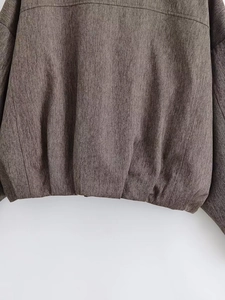 Nahaufnahme der braunen Fischgräten-Stofftextur und des Saumdetails der Damenjacke