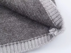 Vue macro de la maille côtelée grise et de la texture douce en laine de cet ensemble pull