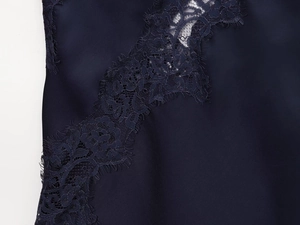 Detailed close-up of dark blue silk fabric with elegant black floral eyelash lace trim