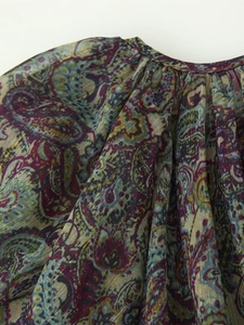 Detailed close-up of paisley print dress with metallic gold thread and pleated neckline