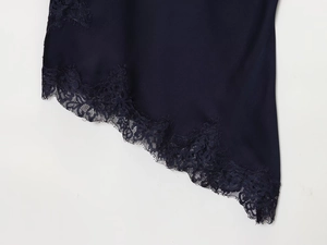 Close-up of navy blue satin fabric featuring delicate lace trim and asymmetrical hem