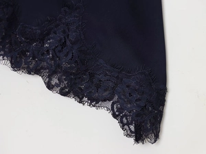 Detailed view of dark blue satin fabric with delicate black eyelash lace trim detail