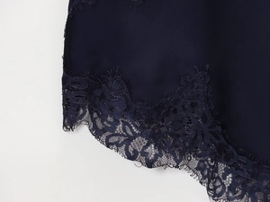 Detail of navy blue satin fabric with delicate floral lace trim on the hemline