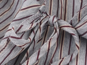 Detail shot of the striped shirt fabric featuring side tie knot and overlock stitch edges