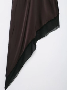 Detail view of asymmetrical dark brown satin hem with black mesh layers and fine texture