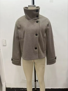 Détail d'un manteau en laine gris avec un col montant et de grands boutons noirs ronds