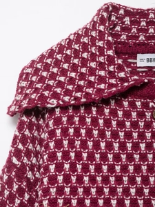Detailed macro view of the soft red and white jacquard knit texture and garment label
