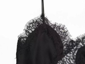 Close-up of black satin camisole featuring delicate eyelash lace trim and thin straps