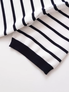 Detail shot of black and white striped knit sweater showing ribbed cuffs and texture