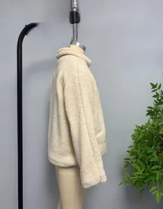 Detailed close-up of thick beige faux shearling jacket with warm textured fleece fabric