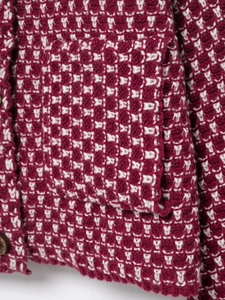 Detailed close-up of red and white tweed knit cardigan with textured pocket and button