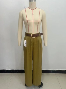 Dettaglio dei pantaloni larghi verde oliva con cintura marrone e fibbia dorata