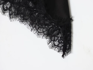 Macro view of silky black satin fabric with delicate eyelash lace trim detail
