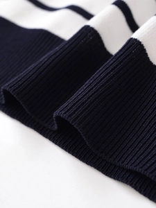 Detailed macro view of the ribbed cuffs on a navy blue and white striped knit sweater