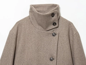 Détail d'une veste courte à col montant avoine avec boutons asymétriques