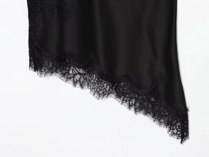 Detailed macro view of black satin fabric with intricate eyelash lace trim on the hemline