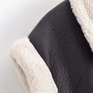 Détail macro de la veste en similicuir noir avec doublure en laine polaire crème douce