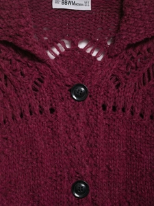 Detail of burgundy crochet knit cardigan featuring lapel collar and dark button accents