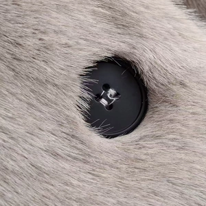 Macro shot of a black cylindrical button on soft grey faux mink fur coat material