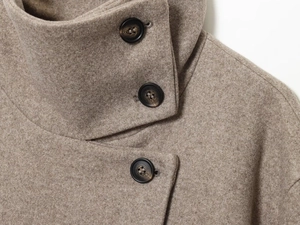 Détail d'une veste en laine camel à col montant avec des boutons en corne et texture douce