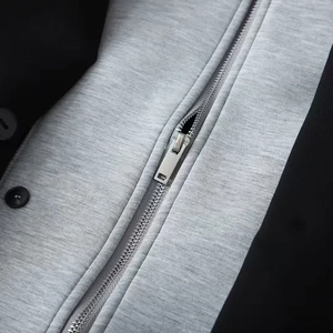 Detailed macro view of gray knitted fabric with silver metal zipper and black button detail
